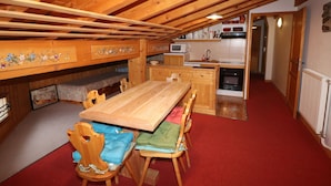 A cozy kitchen with wooden cabinets, a dining table, and chairs. There is a microwave and a sink in the kitchen area. - Comfortable Apartment in the Heart of Tignes le Lac, Ideal for 6 People (Tignes)