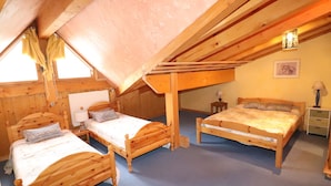 A cozy attic bedroom with two wooden beds, a small table, and a lamp. - Comfortable Apartment in the Heart of Tignes le Lac, Ideal for 6 People (Tignes)