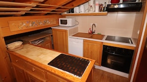 A compact kitchen with wooden cabinets, a microwave, a dishwasher, and a stove. - Comfortable Apartment in the Heart of Tignes le Lac, Ideal for 6 People (Tignes)