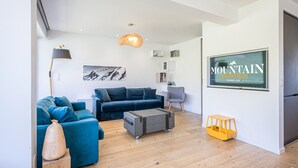 A modern living room with a sofa, a coffee table, and a television mounted on the wall.