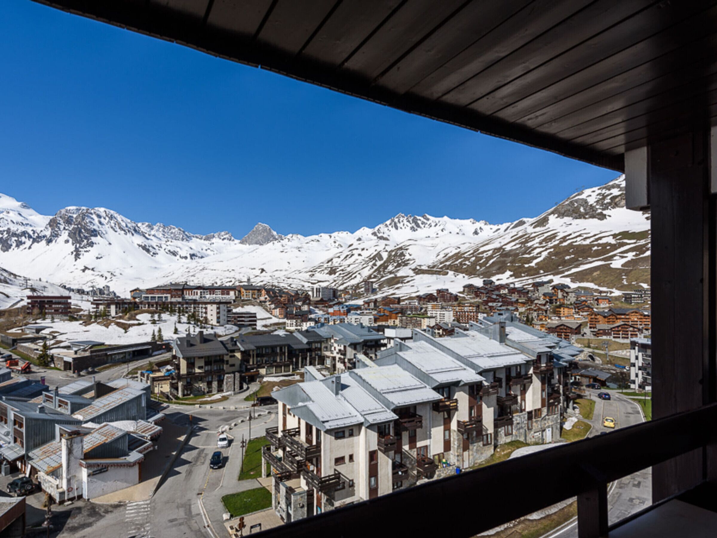Une ville dominée par des montagnes enneigées, avec des bâtiments modernes et un ciel bleu dégagé.