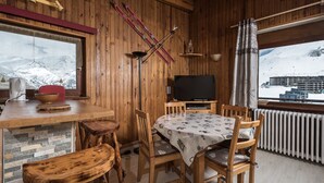 En inredning med träpanel, ett matbord, stolar, en tv och ett par skidor som hänger på väggen.