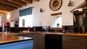 Une cuisine moderne avec des meubles en bois, un lave-vaisselle, une machine à café et une horloge au mur.