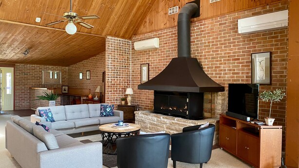 A cozy living room with a fireplace, a sofa, a coffee table, and a TV. - Bluebush Estate - The Lodge (Rothbury)