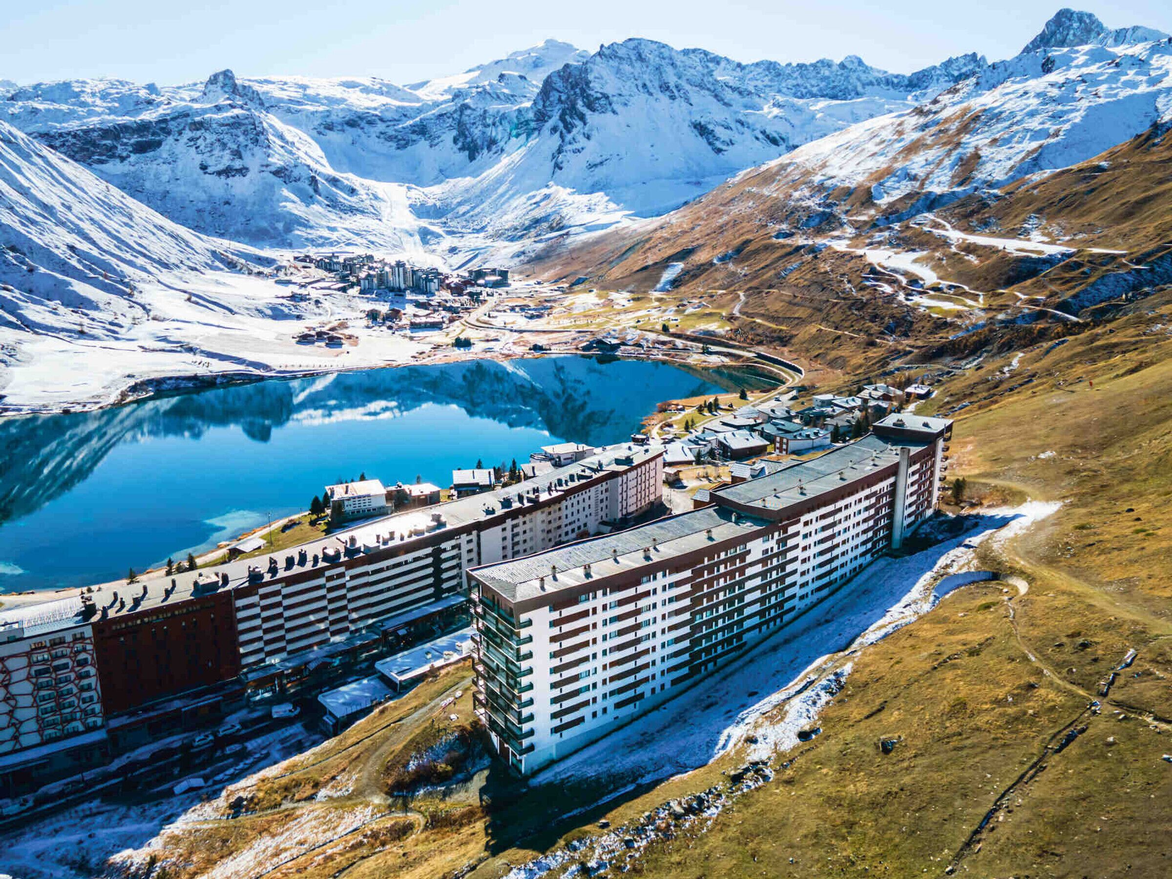 A hotel with multiple floors, located near a lake and mountains.