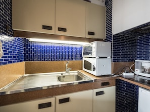 Una cocina con un lavamanos de acero inoxidable, doble microondas y una cafetera.