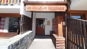 Une entrée d’immeuble avec une enseigne en bois sur laquelle on peut lire : « LES NOUVELLES RÉSIDENCES ».