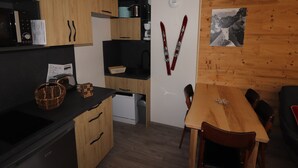 Una cocina compacta con armarios de madera, encimera negra y un comedor con mesa y sillas de madera.