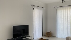 Ein modernes Wohnzimmer mit einem Flachbildfernseher, einem schwarzen Couchtisch und einem beigen Sofa.