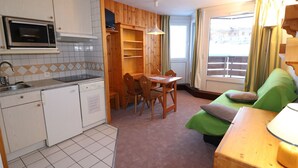 A compact room with a kitchenette, a dining area, and a bed.