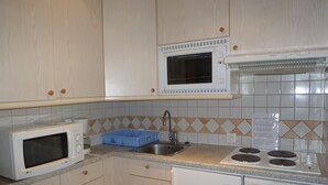 A compact kitchen with a microwave, stove, sink, and dishwasher.