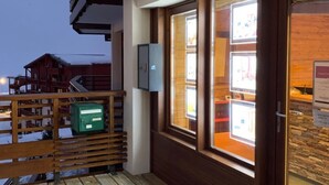 A wooden balcony with a view of a building and a signboard.