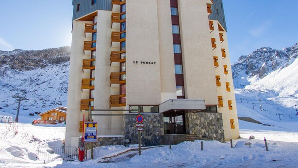 A multi-story hotel with a ski lift in the background.