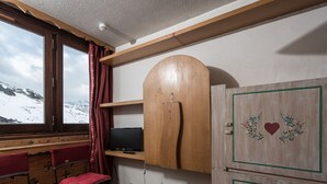 A room with a wooden desk, two chairs, a television, and a wooden wardrobe with decorative elements. - Practical studio at the foot of slopes - Pets allowed (Tignes)