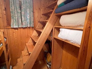 A wooden attic room with a sloped ceiling, a window with floral curtains, and a bed with white bedding. - Wooden chalet with terrace and garden in Barcelonnette (Barcelonnette)
