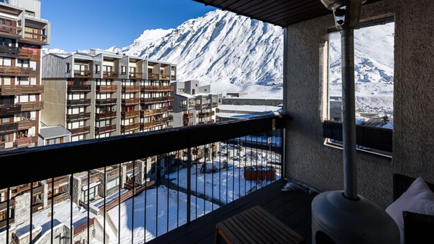 A balcony with a view of a snow-covered mountain and modern buildings.