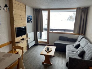 Relax in this inviting living room with a comfortable sofa, coffee table, and large window offering a scenic view.