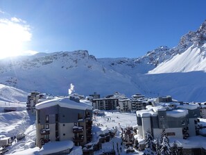 Een bergresort bedekt met sneeuw, met meerdere gebouwen, skiliften en een heldere lucht.