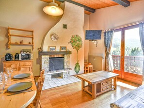 A cozy room with a fireplace, wooden furniture, and a television. - Charming 2-Bedroom Apartment for 6 in Quiet Area with Shuttle Access (Les Gets)