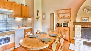 Eine gemütliche Küche mit Holzausstattung, einem Esstisch für vier Personen und einem Kamin.