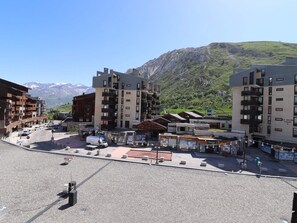 A modern building with multiple floors, a central courtyard, and a mountain backdrop. - Functional Studio Near Slopes with Balcony (Tignes)