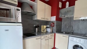 Eine kompakte Küche mit Mikrowelle, Toaster, Spüle und Waschmaschine.