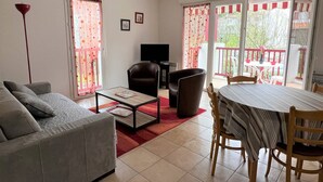 Ein Wohnzimmer mit einer Couch, einem Couchtisch, einem Fernseher und einem Essbereich mit Tisch und Stühlen.