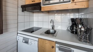 Et kompakt køkken med træskabe, en mikrobølgeovn, en opvaskemaskine og en vask.