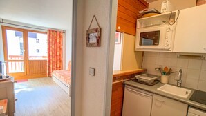A compact kitchen with a microwave, sink, and dishwasher. A small dining area with a table and chairs is visible in the background.