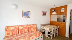 A small, cozy room with a sofa, a table, and a wooden cabinet.