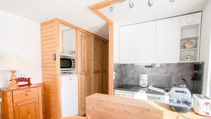 A compact kitchen with wooden cabinets, a microwave, a coffee maker, and a toaster.