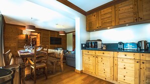 A wooden interior with a dining area, kitchen, and a television mounted on the wall. - Renovated ski-in ski-out apartment, balcony, WIFI, 4 bedrooms (Tignes)