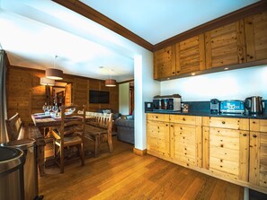 Un interno in legno con zona pranzo, cucina e televisore a parete.
