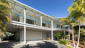 Una casa de dos pisos con un porche cubierto, garaje y piscina.