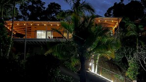 Ein modernes Haus mit überdachter Terrasse, umgeben von üppiger Vegetation.