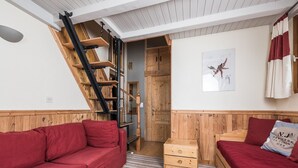 Ein gemütliches Zimmer mit einem roten Sofa, einer Holzkiste und einer Treppe, die zu einem Erker führt.