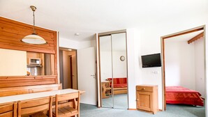 Ein Zimmer mit einem Holztisch, einem roten Sofa, einem Fernseher und einem Spiegel.