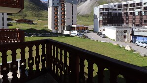 A hotel with a balcony overlooking a mountainous landscape, featuring modern architecture and a parking area.