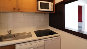 A compact kitchen with wooden cabinets, a microwave, a dishwasher, and a window with a view.