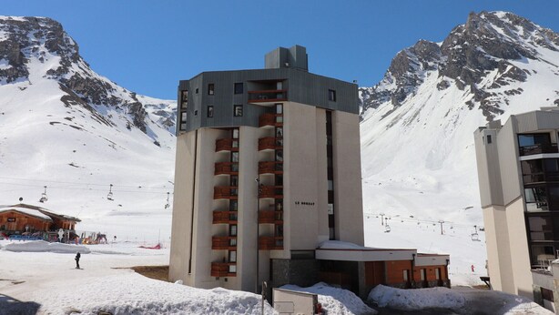 A modern hotel with a ski lift in the background, surrounded by snow-covered mountains.