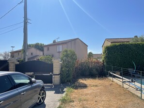 Zona residencial con entrada vigilada, un coche estacionado y una piscina.