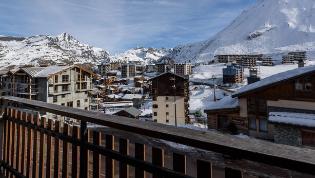 A snow-covered mountain town with wooden buildings and a ski lift.