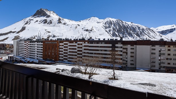 Un hotel de varios pisos, un paisaje nevado y una montaña al fondo.