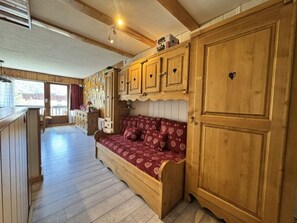 A wooden interior with a sofa, cabinets, and a window.
