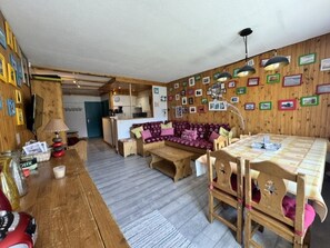 A cozy room with a wooden floor, a sofa, a table, and a kitchen area.
