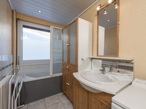 Un bagno con una vasca, due lavabi, uno specchio e una finestra.