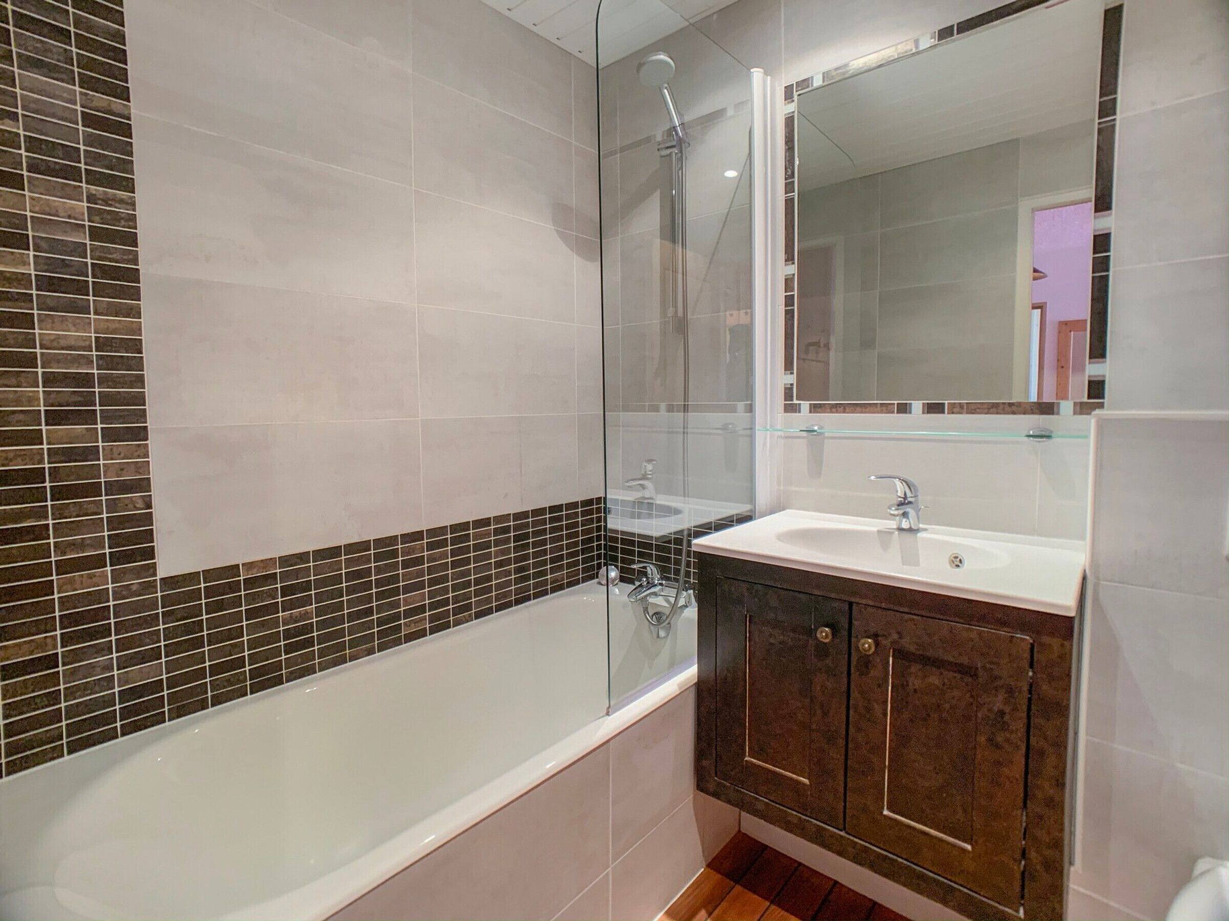 Une salle de bain moderne avec une baignoire, une douche à l’italienne avec des parois en verre, un meuble-lavabo et un grand miroir.