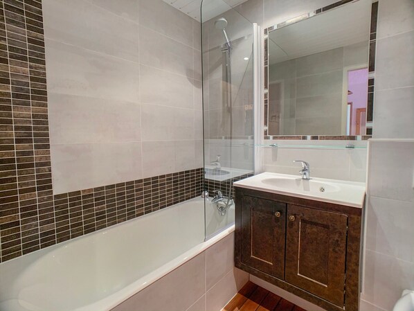 Un baño moderno con bañera, cabina de ducha de vidrio, tocador con lavabo y un espejo grande.