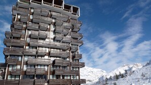 A multi-story building with a unique wooden facade, set against a snowy mountainous backdrop. - Renovated Studio 2 Pers. Close to Slopes with Balcony (Tignes)