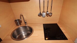 A kitchen with a stainless steel sink, a black induction cooktop, and a set of kitchen utensils hanging above the sink. - Renovated Studio 2 Pers. Close to Slopes with Balcony (Tignes)